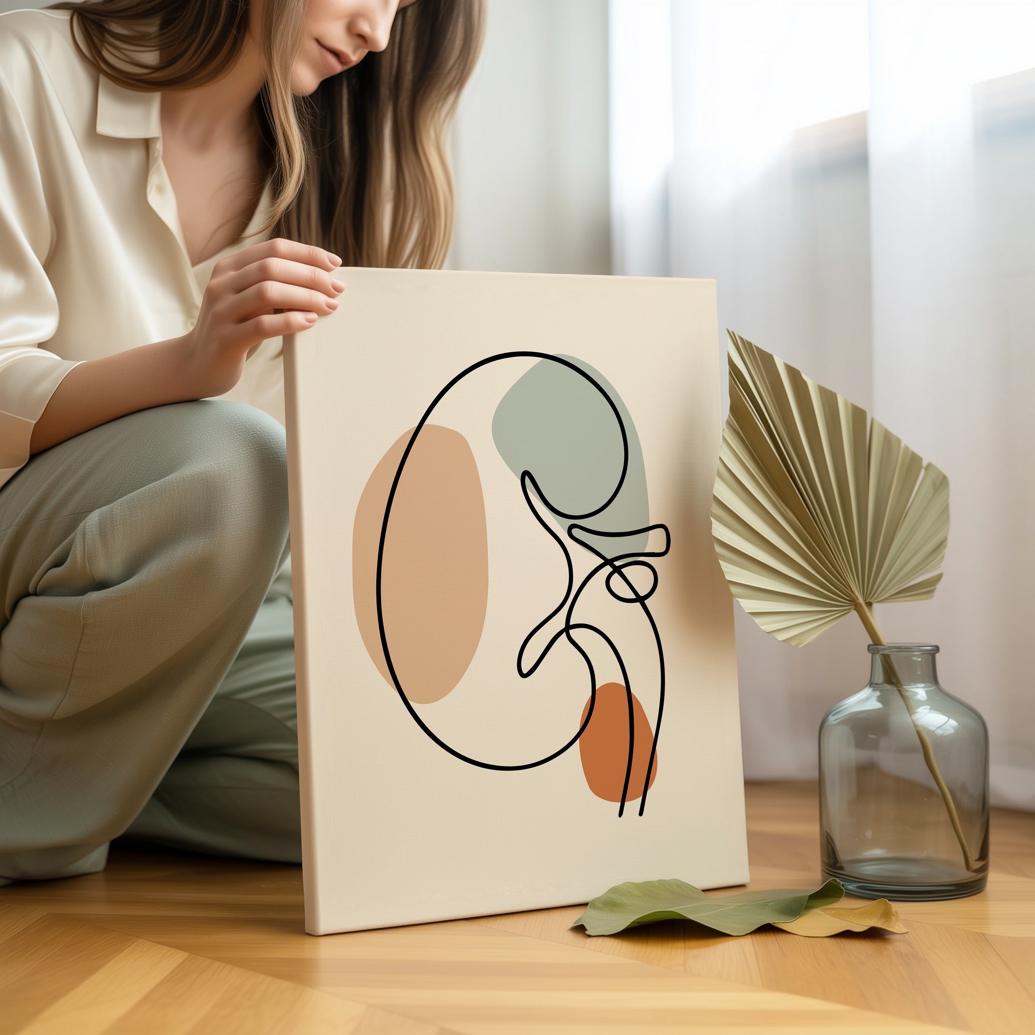 Minimalist kidney line art held by a person in a bright neutral room.