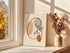 Minimalist kidney line art displayed beside a bright window.
