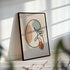 Minimalist kidney line art in a black frame with striped sunlight across the wall.