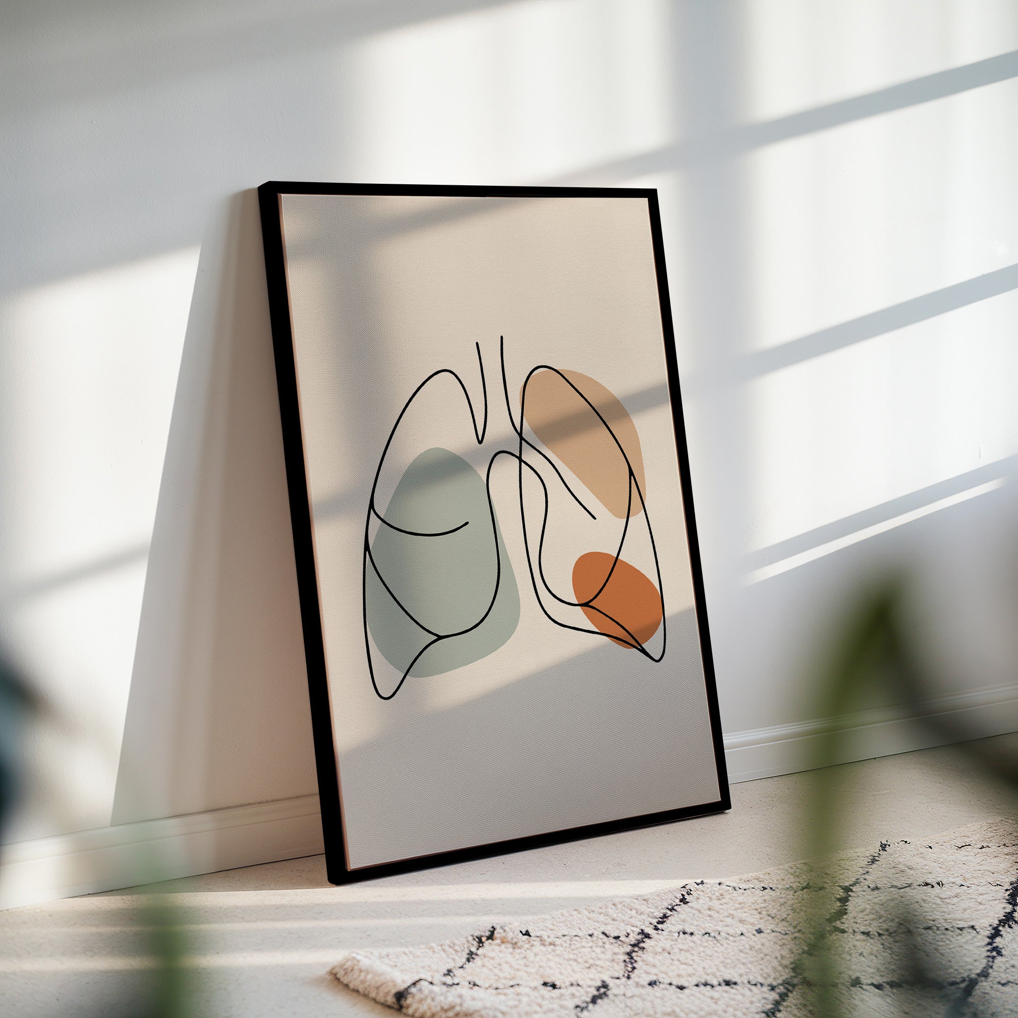Black framed one line lungs art leaning against a wall in a sunlit room