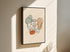 Pelvis anatomy artwork on framed canvas with a black outer frame on a sunlit beige wall.