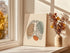 Minimalist rib cage line art displayed beside a bright window.