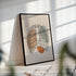 Minimalist rib cage line art in a black frame with striped sunlight across the wall.
