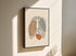 Minimalist rib cage line art on canvas in a black outer frame on a sunlit wall.