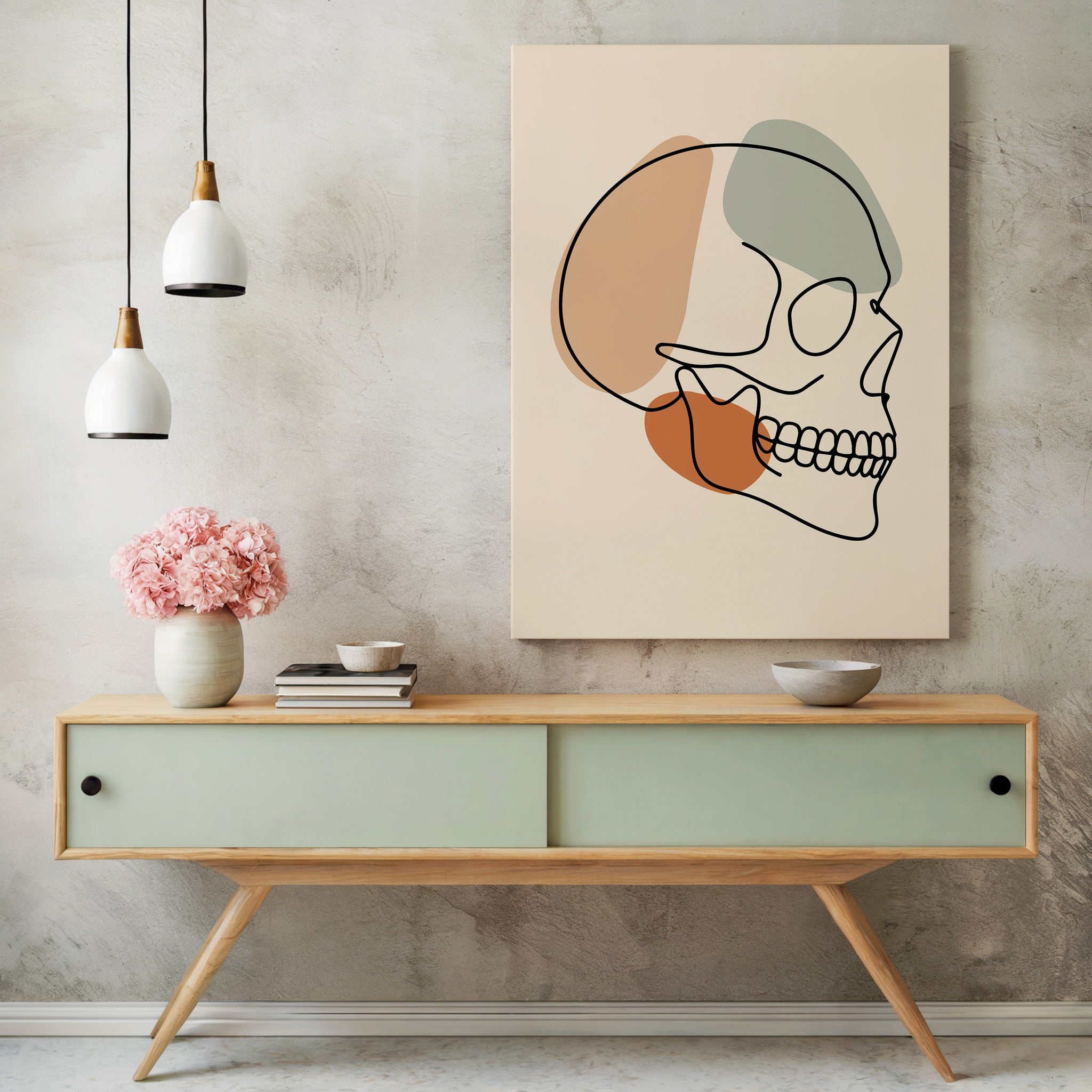 Minimalist skull line art above a green sideboard with flowers and pendant lighting.