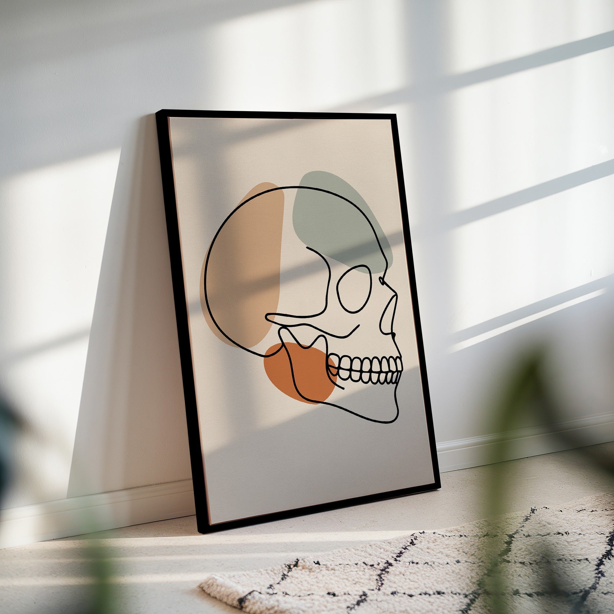 Minimalist skull line art in a black frame with striped sunlight across the wall.