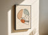 Minimalist skull line art on canvas in a black outer frame on a sunlit wall.