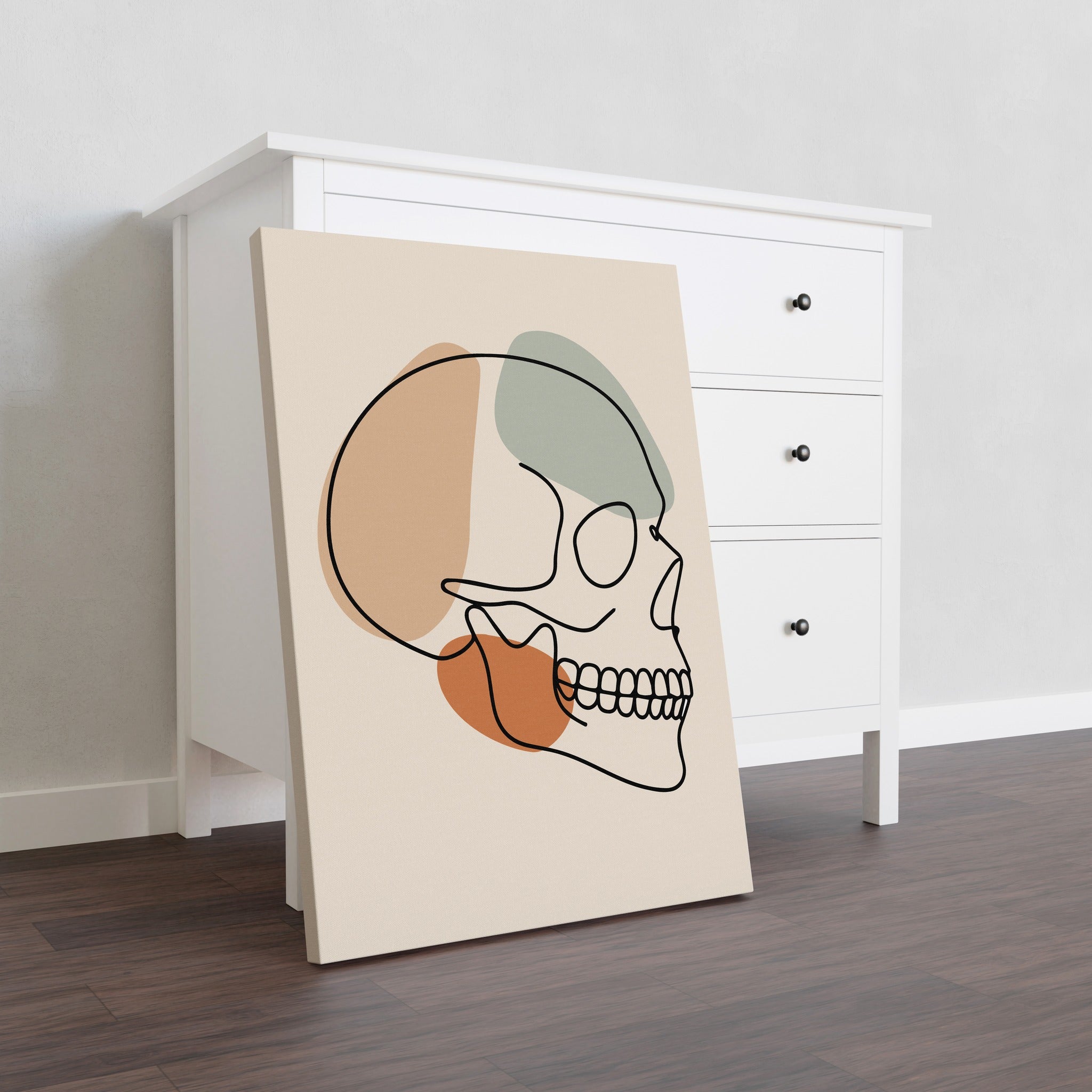 Minimalist skull line art on stretched canvas beside a dresser.