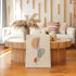 Spine anatomy canvas leaning in front of a round wooden coffee table in a bright living room.