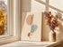 Spine line art canvas beside a vase of dried flowers on a sunny windowsill.