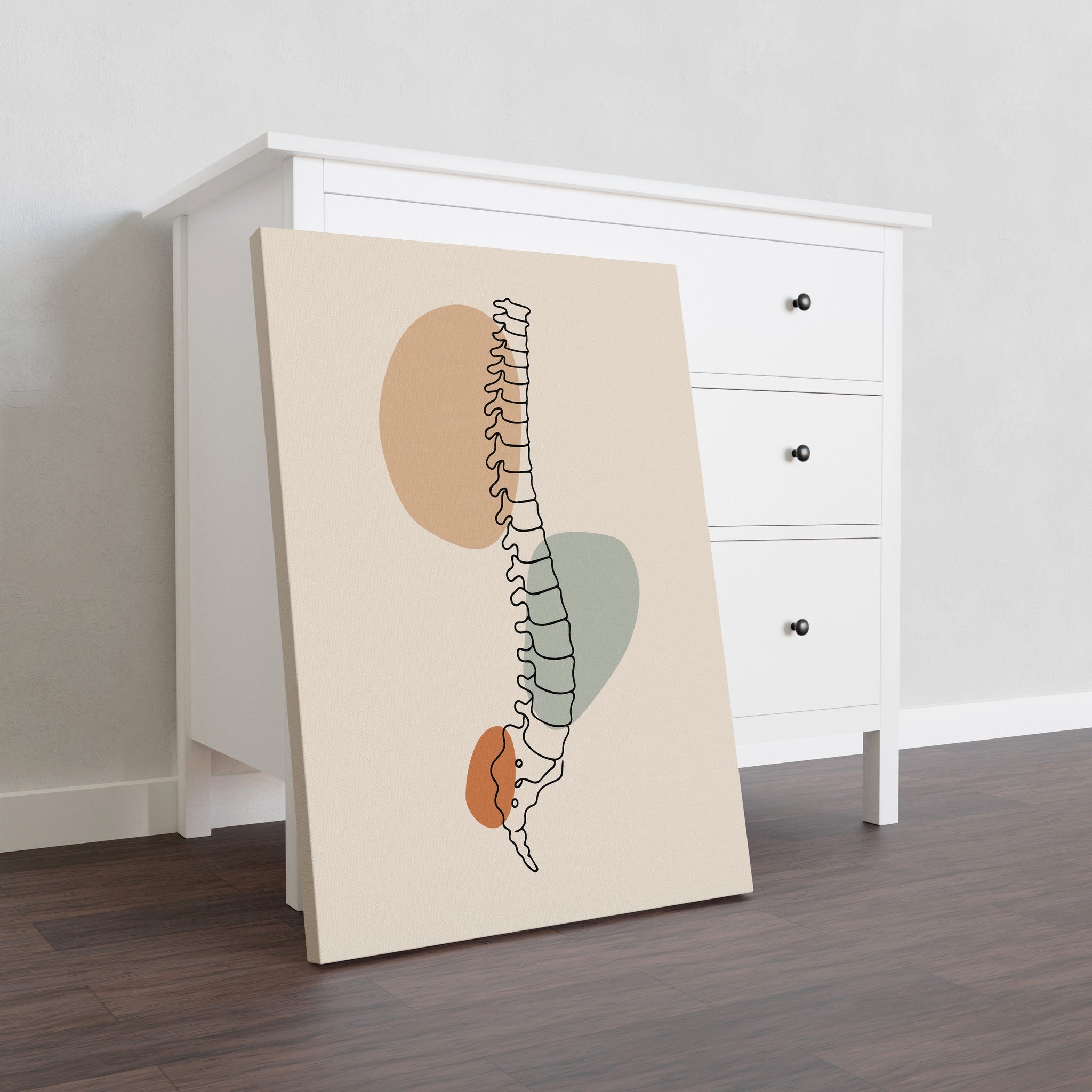 Unframed stretched canvas with minimalist spine artwork leaning against a white dresser.